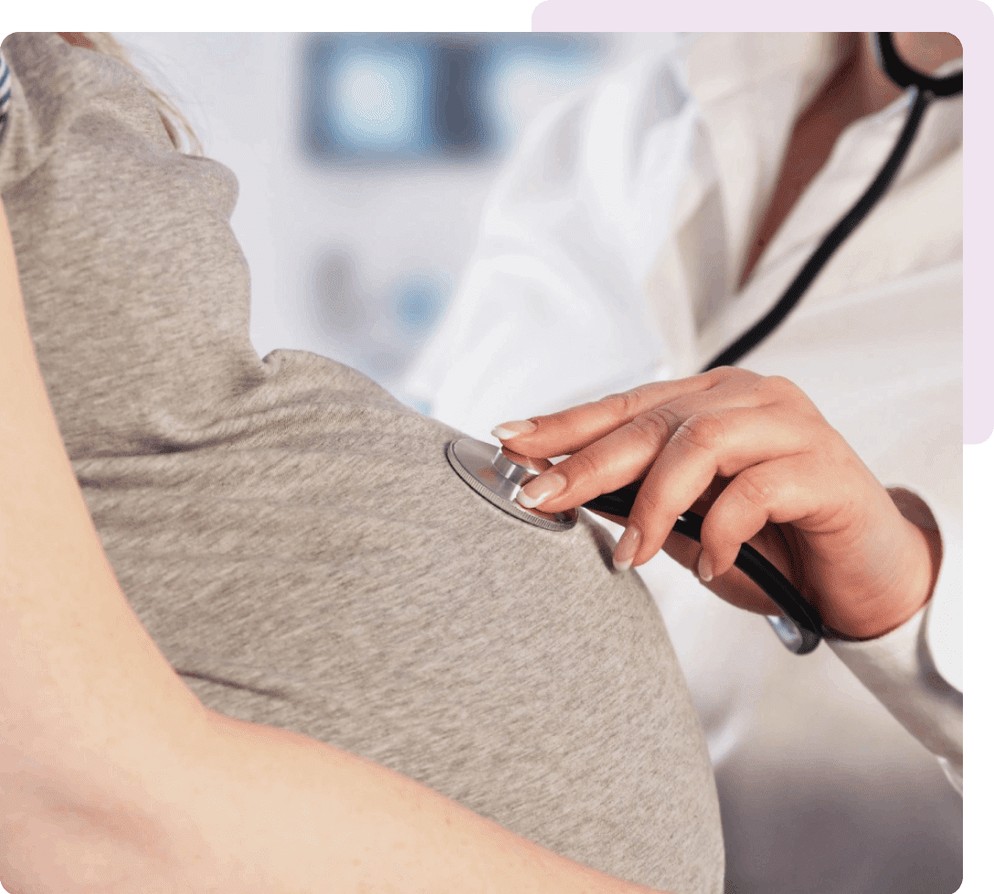 Doctor listening to pregnant woman's belly with stethoscope