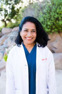 Smiling woman physician outdoors in white coat